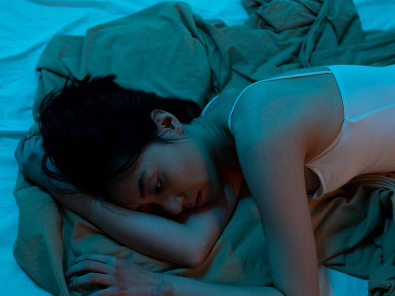 A Woman in White Tank Top Lying on Bed
