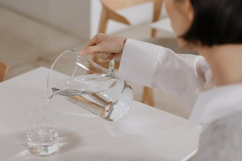 A Woman Pouring Drinking Water in a Glass