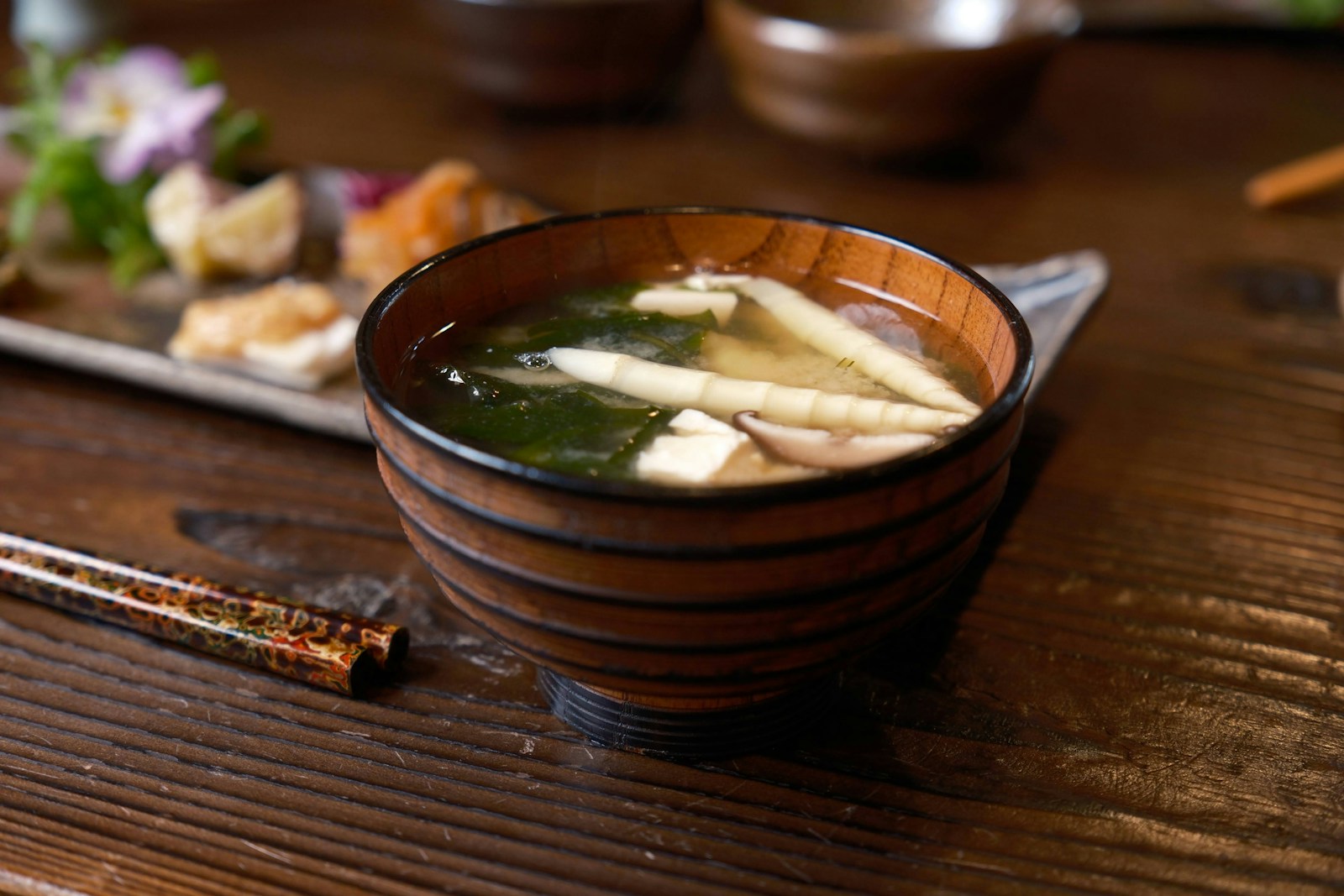 a wooden bowl filled with soup next to chopsticks